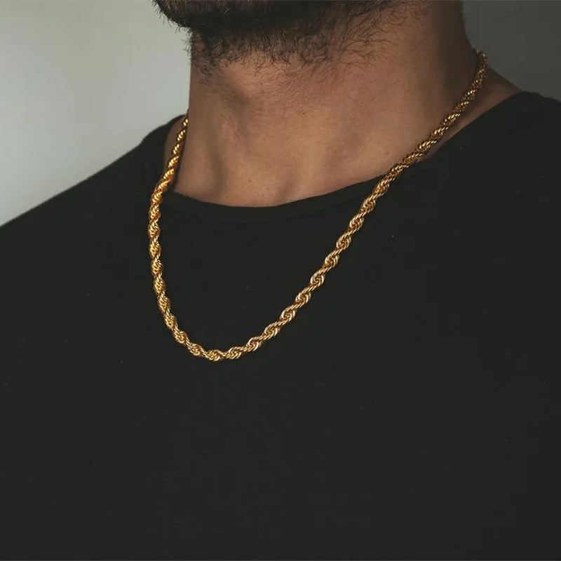 Gold rope chain necklace on a person wearing a black shirt against a neutral background