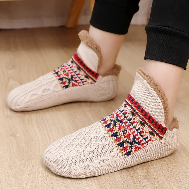 White knitted slippers with patterned sole on a wooden floor