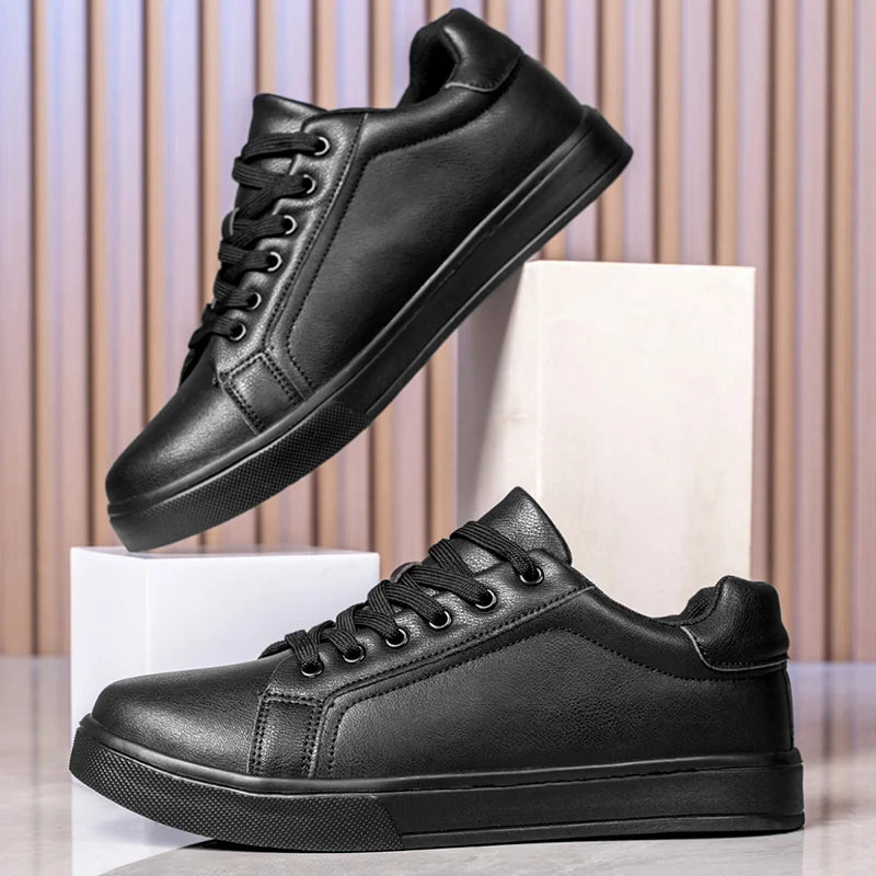 Two black leather sneakers on a light background