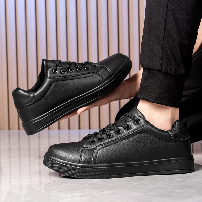 Black leather sneakers worn with a suit on a neutral background
