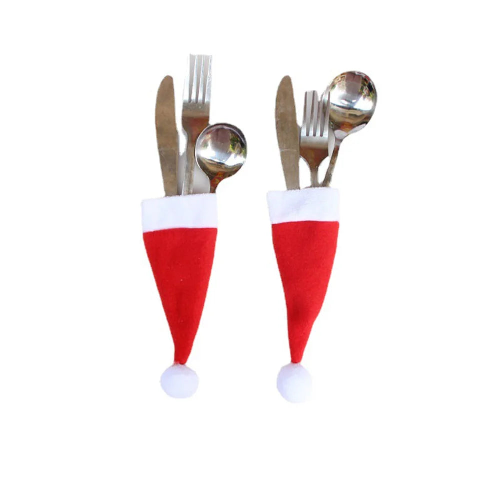 Set of silver cutlery with Santa hat covers on a white background