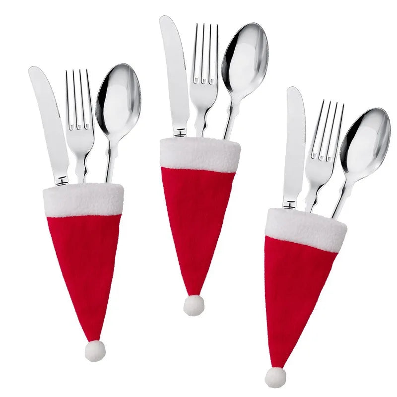 Set of silver cutlery with Santa hats on a white background
