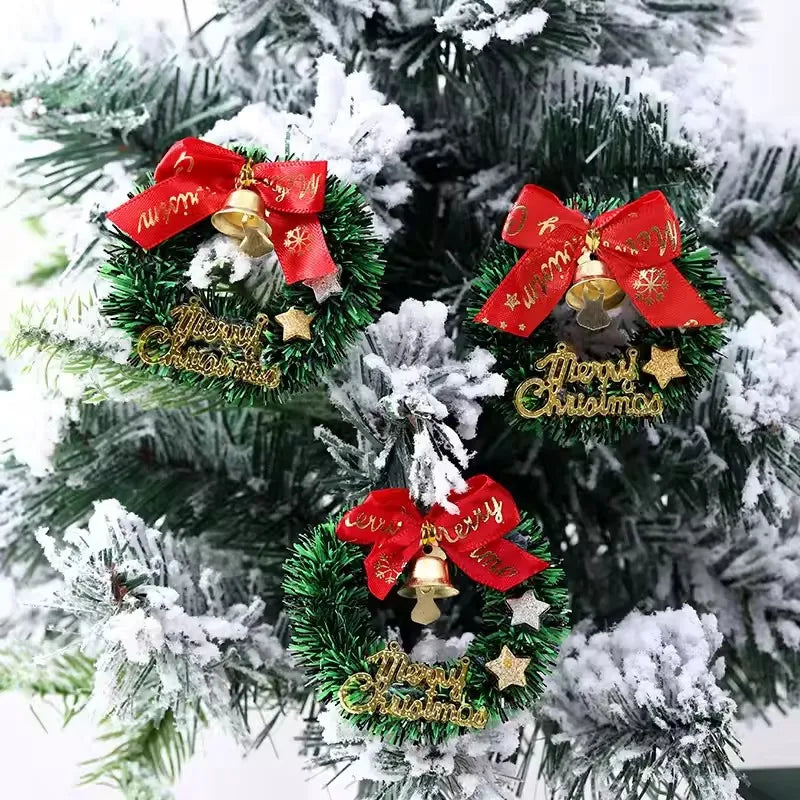 Three festive Christmas wreath ornaments with red bows and gold bells on a snow-covered tree.
