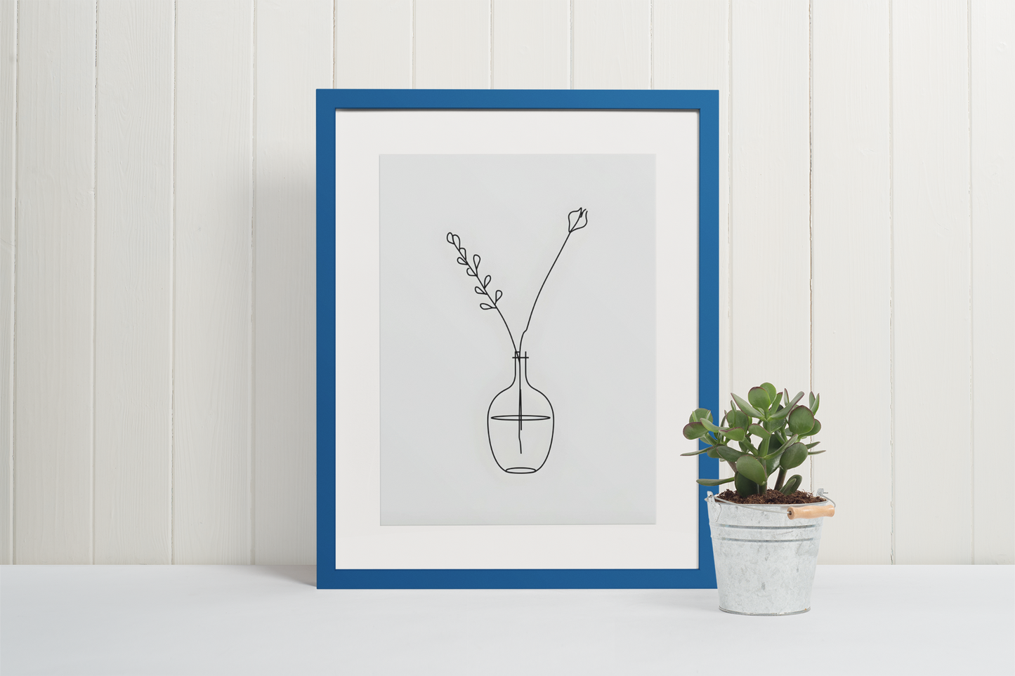 Framed minimalist line art of a vase with a plant on a white surface.