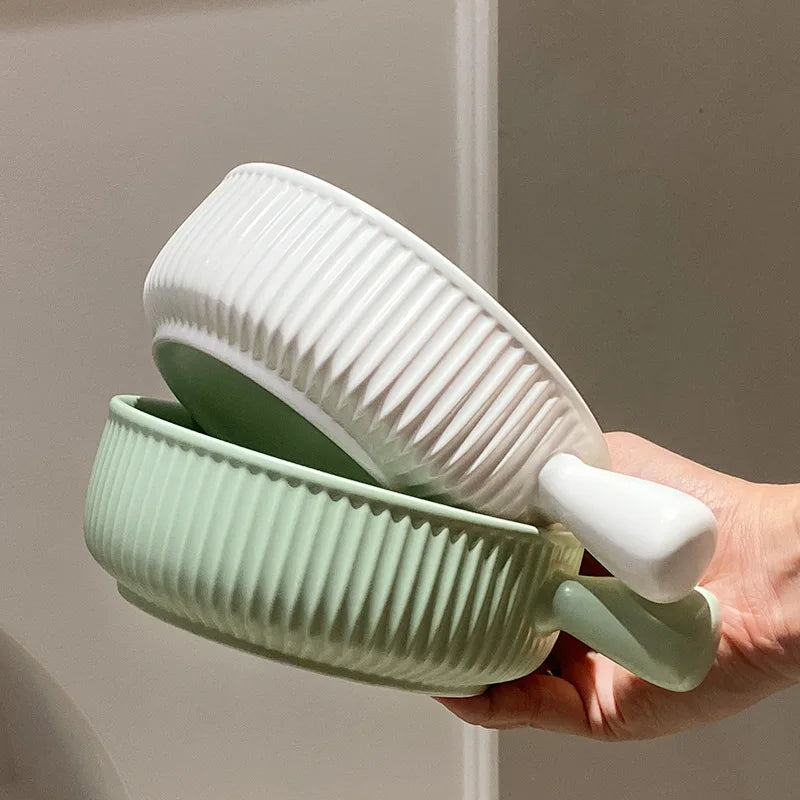 Hand holding a green and white textured dish against a neutral background