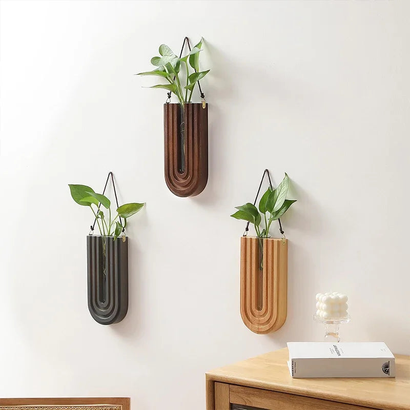 Three wall-mounted planters in different colors on a light-colored wall.