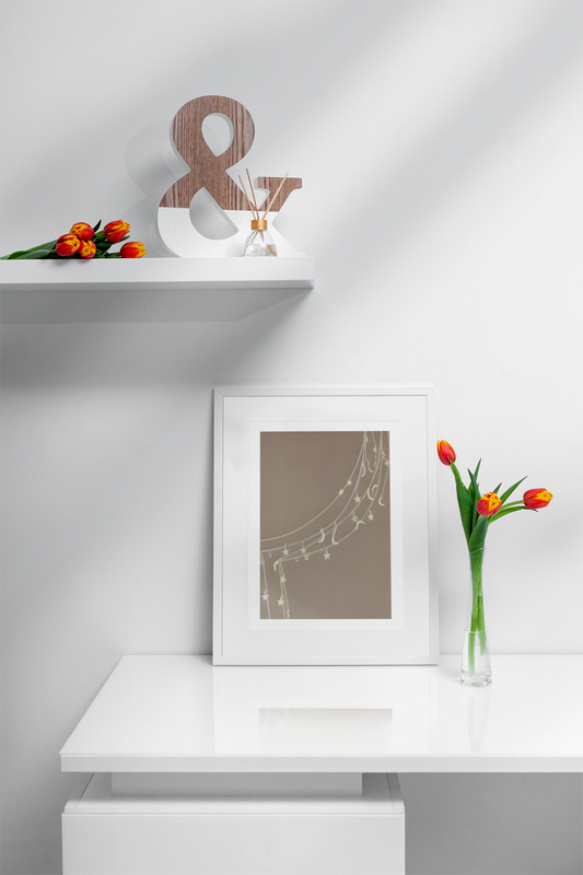 Decorative setup with a framed picture of Celestial Moon and Stars Wall Art, flowers, and a shelf on a white wall.