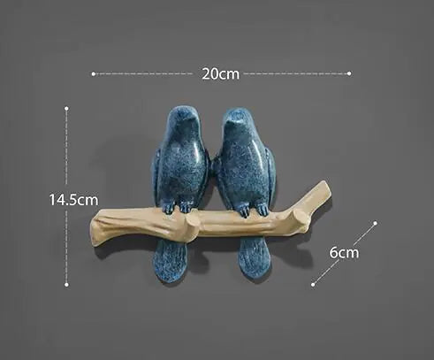 Two blue ceramic birds on a branch with measurements on a gray background