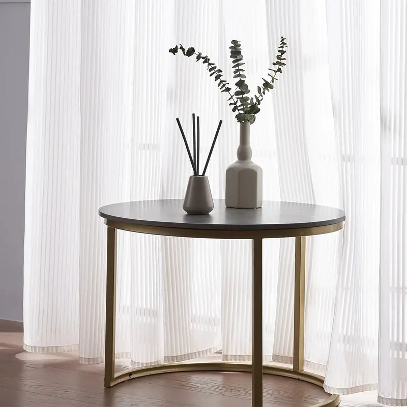 Small round table with decorative items against a white curtain backdrop