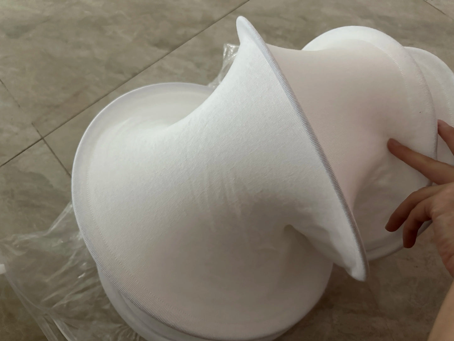 White silicone cupping device held by a hand on a tiled floor.