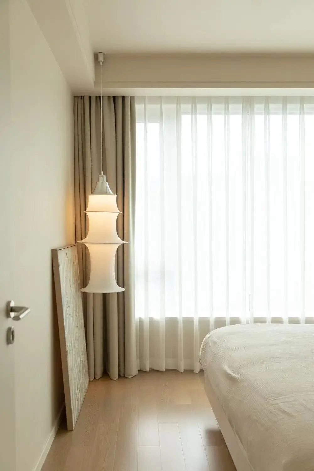 Modern bedroom with a bed, lamp, and curtains.