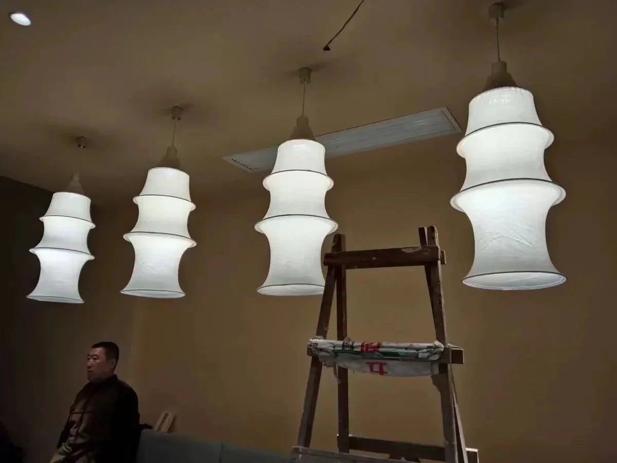 White pendant lights hanging from the ceiling with a person and ladder in the foreground.