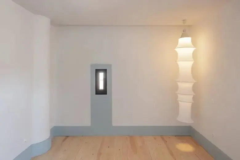 Empty room with a light fixture on a white wall.