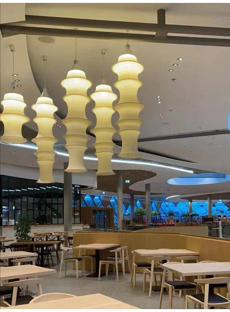 Modern restaurant interior with tables, chairs, and decorative ceiling lights.