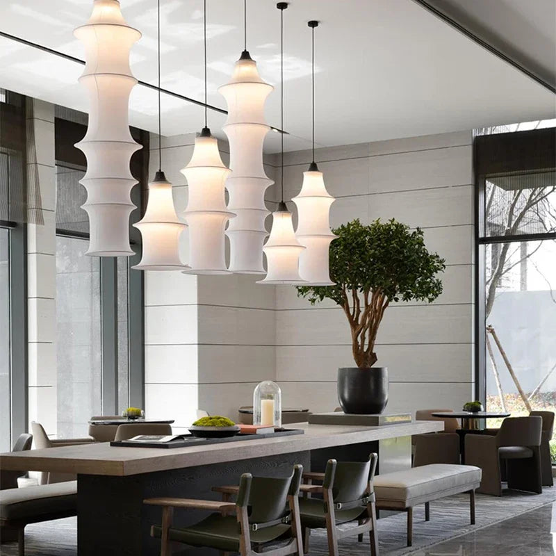 Modern dining area with pendant lights, table, chairs, and a plant.