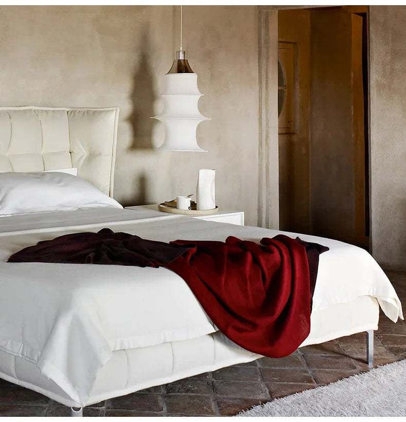 Bedroom with a bed featuring a red blanket and a beige headboard.