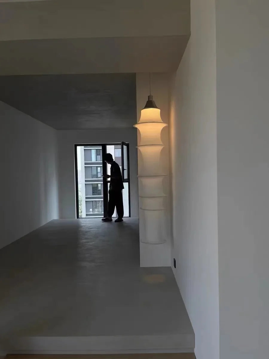 Person standing in a room with a large mirror reflecting a building exterior.