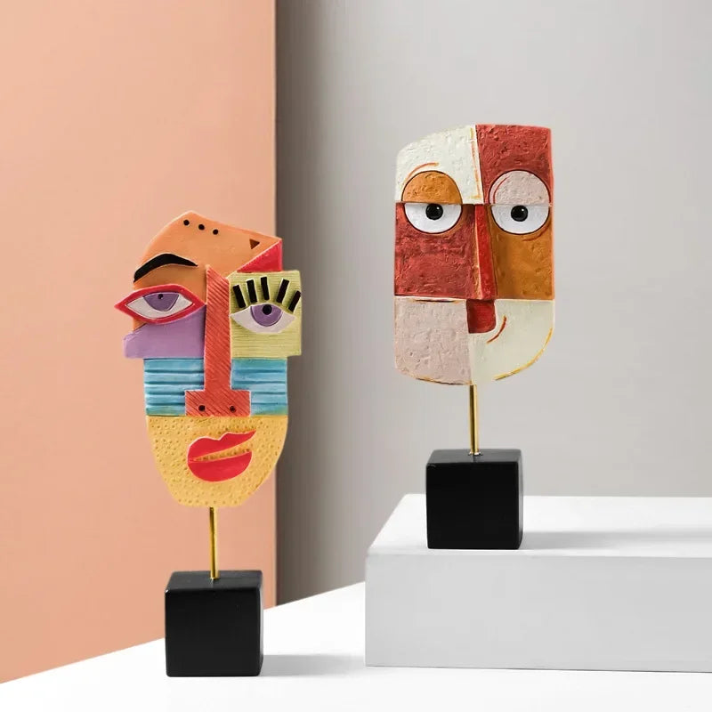 Two abstract face sculptures on stands against a minimal background