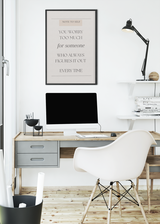 Modern home office with a desk, chair, computer monitor, and framed quote on the wall.