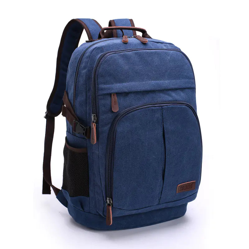 Large blue canvas backpack with leather accents and multiple compartments, standing upright against a plain background