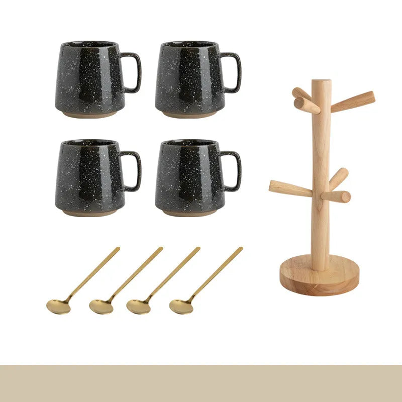 Set of black speckled mugs, wooden spoons, and a wooden mug tree on a white background.
