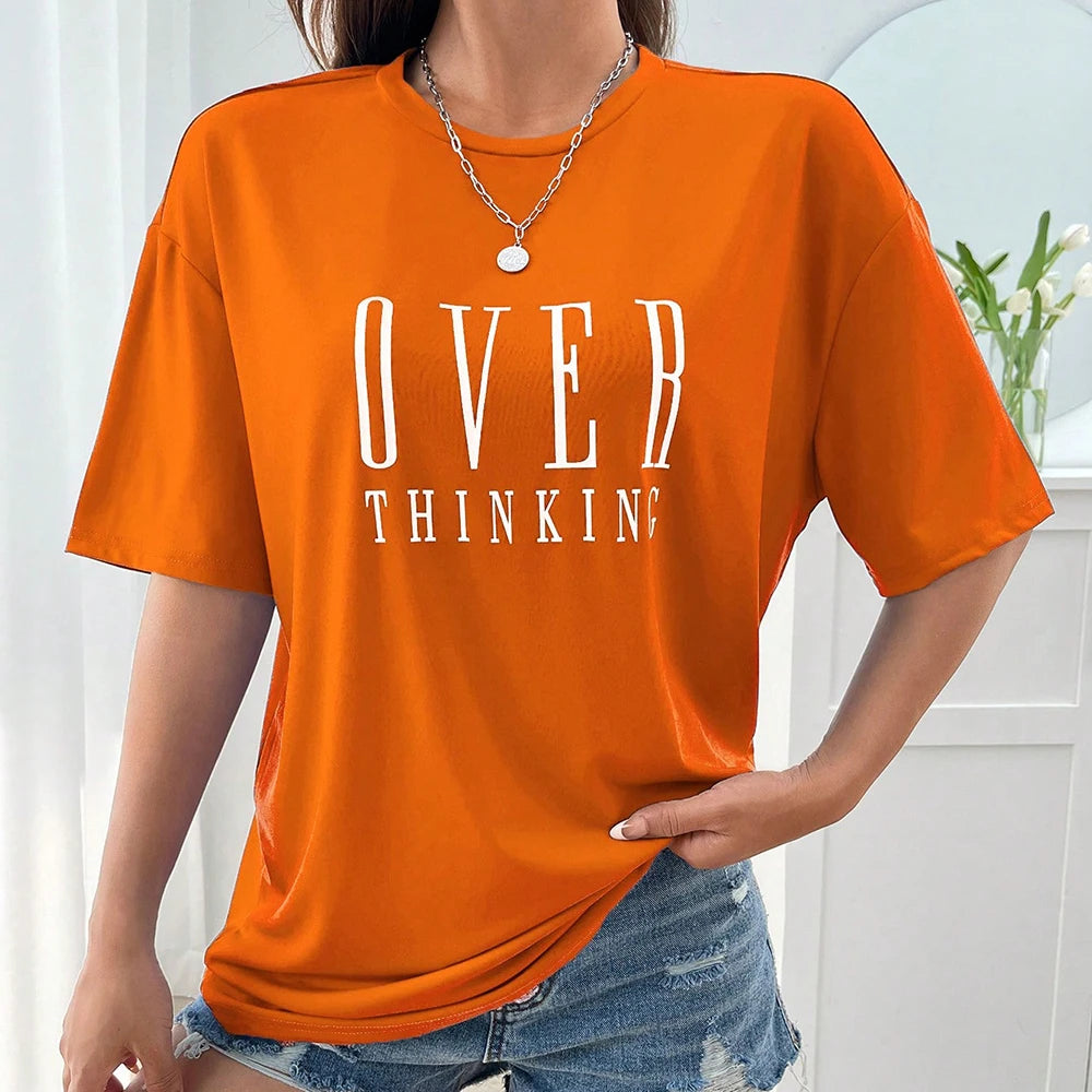 Person wearing an orange t-shirt with 'OVER THINKING' text, standing indoors.