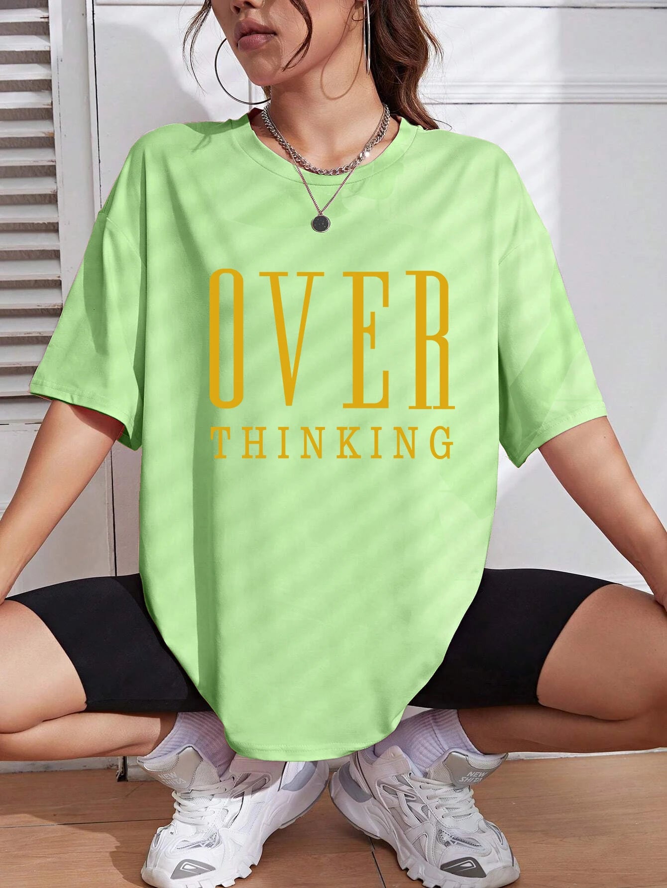 Person wearing a light green t-shirt with 'OVER THINKING' text, sitting on the floor.