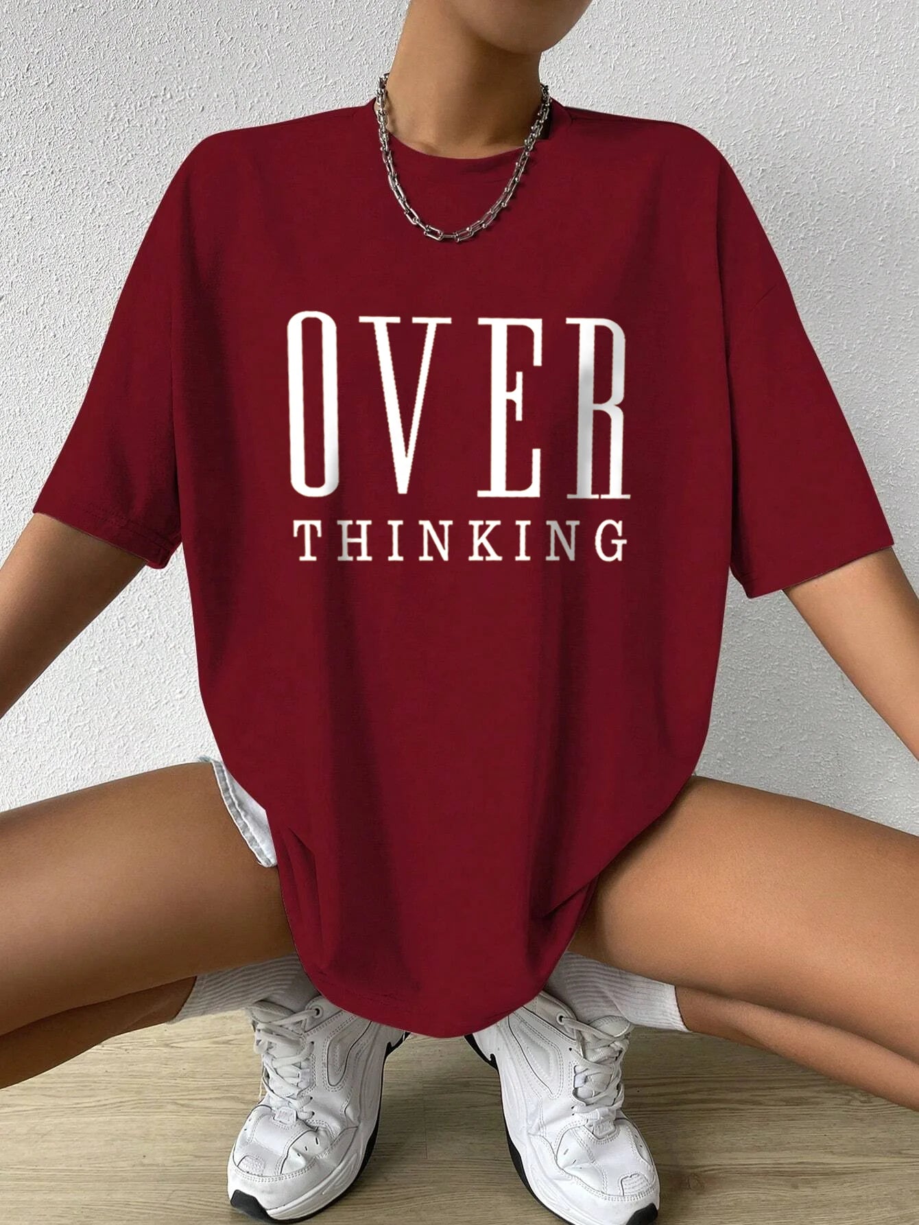 Person wearing a red t-shirt with 'OVER THINKING' text, sitting on the floor.