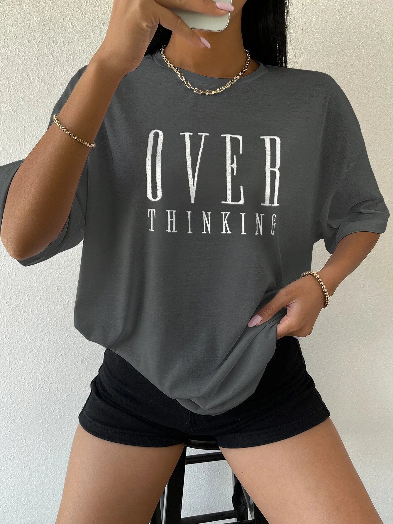 Person wearing a gray t-shirt with 'OVER THINKING' text against a plain background