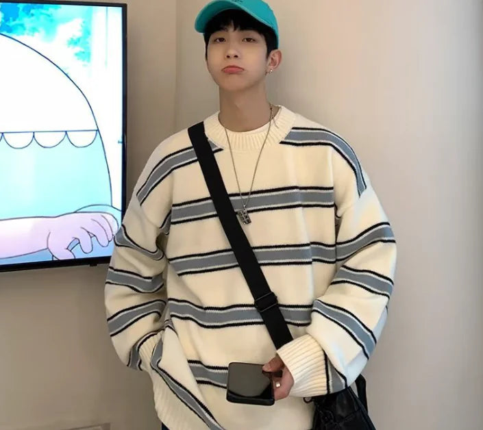 Person wearing a striped sweater and cap indoors with a screen in the background