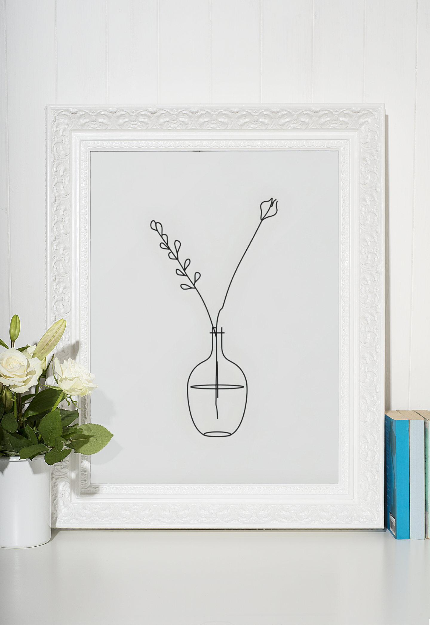 Framed line drawing of a vase with flowers on a white surface
