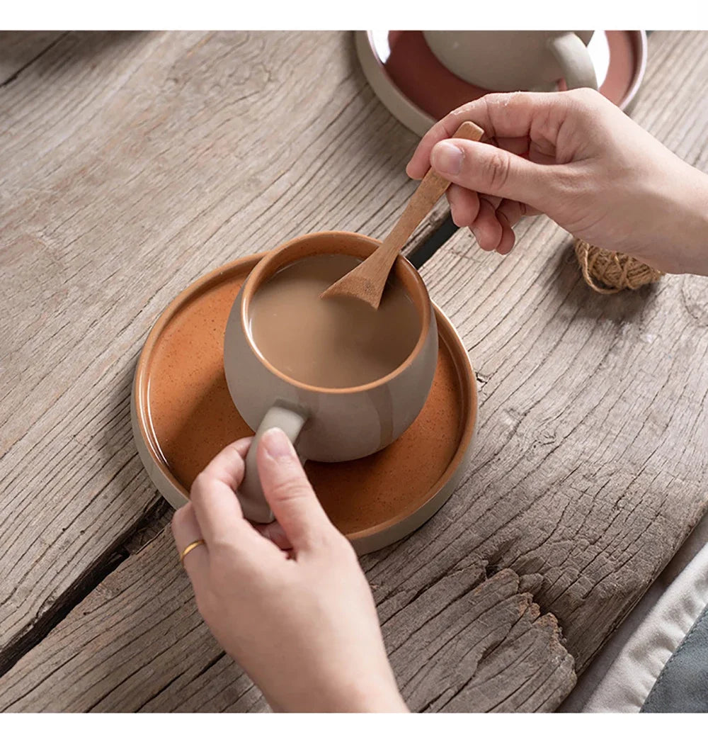 Person holding a ceramic mug with a wooden spoon on a wooden surface