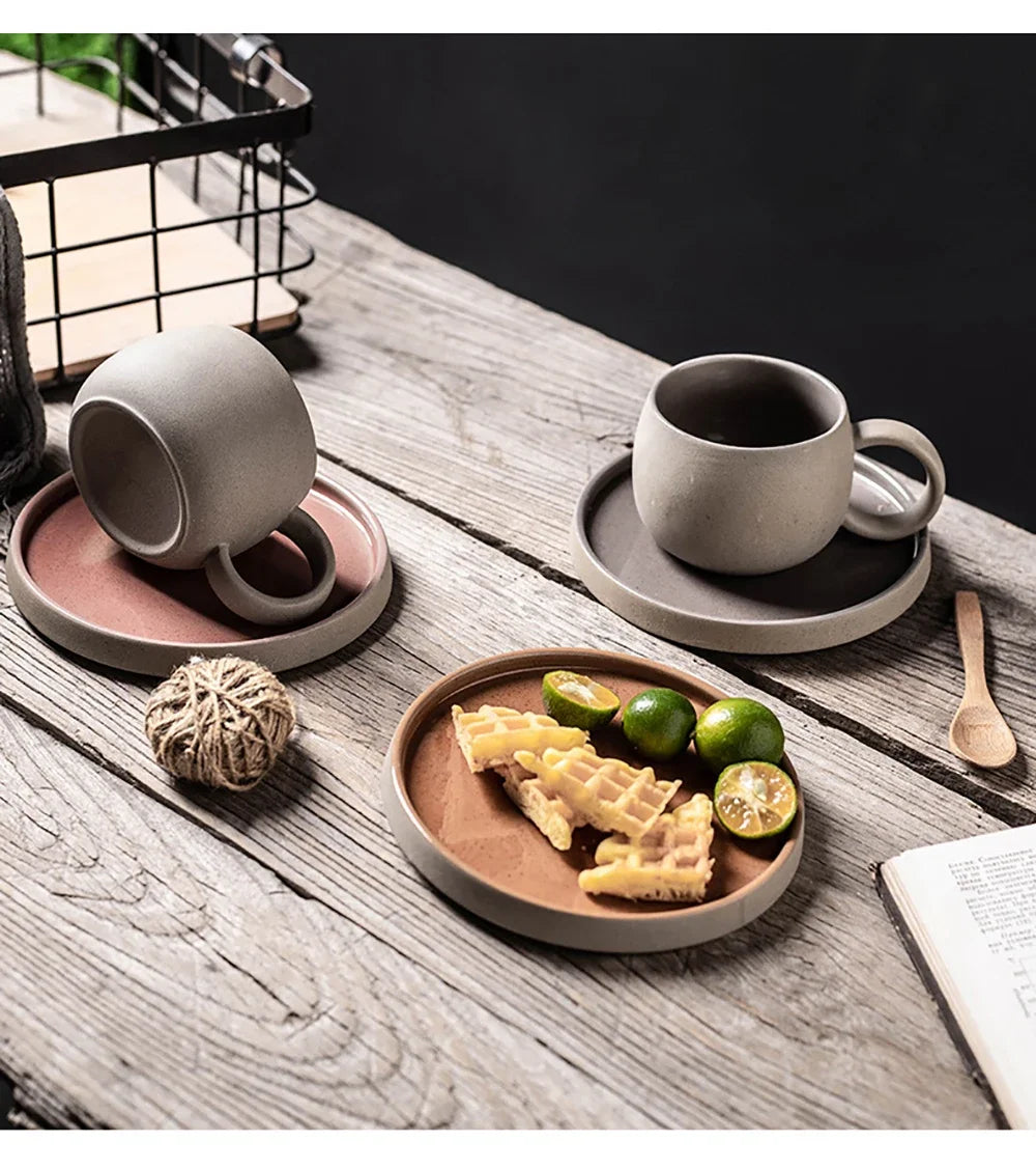 Ceramic cups and plates on a wooden table with food and decor items.