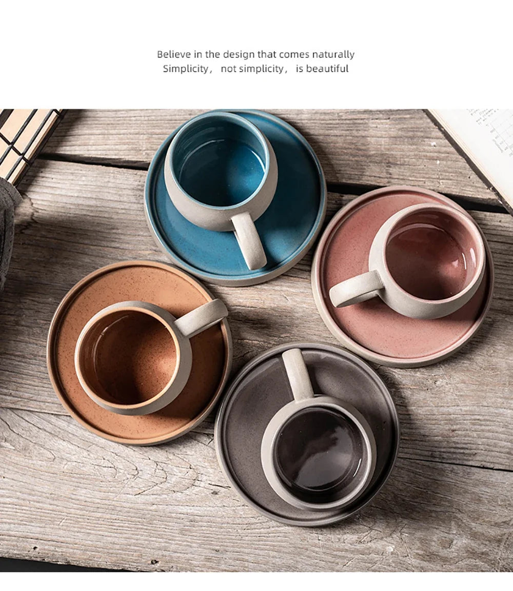 Four ceramic cups with saucers in different colors on a wooden surface.