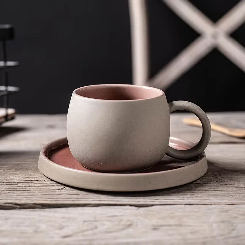 Ceramic mug with pink interior and exterior on a matching coaster on a wooden surface.