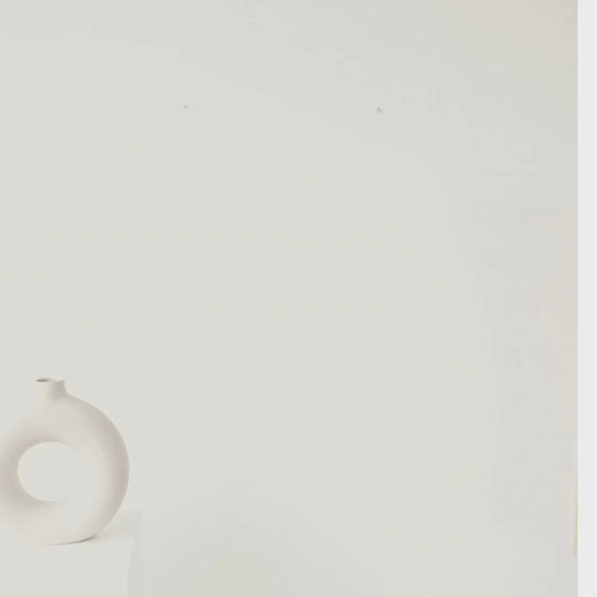 Woman hanging the Amplified scientific sound wave poster in a modern home, showcasing minimalist speaker artwork with striking electric blue accents.