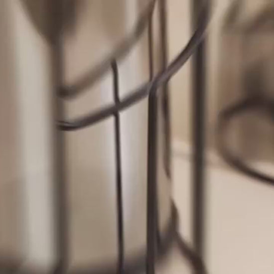 Video of  two modern black spiral glass candle holders with smoked hurricane glass displayed on a wooden table in a contemporary home interior.