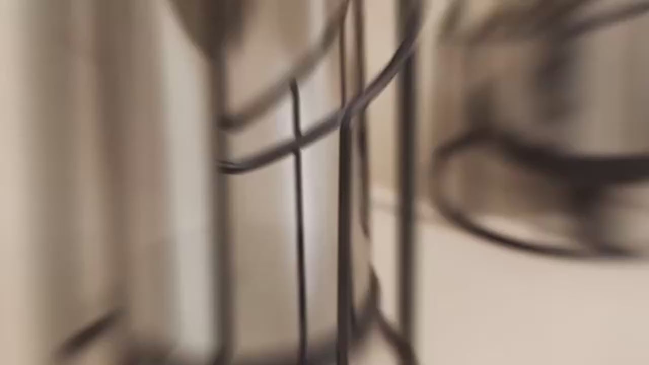 Video of  two modern black spiral glass candle holders with smoked hurricane glass displayed on a wooden table in a contemporary home interior.