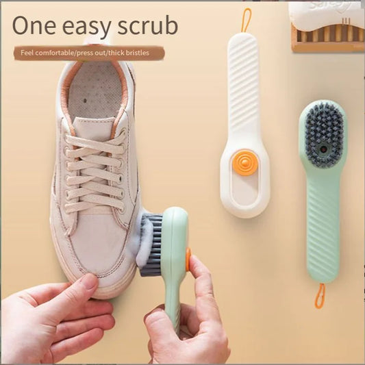 Hand using soap-dispensing scrub brush on sneaker with two additional brushes shown above, demonstrating design and thick bristles.