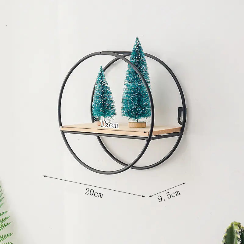 Wall-mounted round metal shelf with two small green trees on a white background