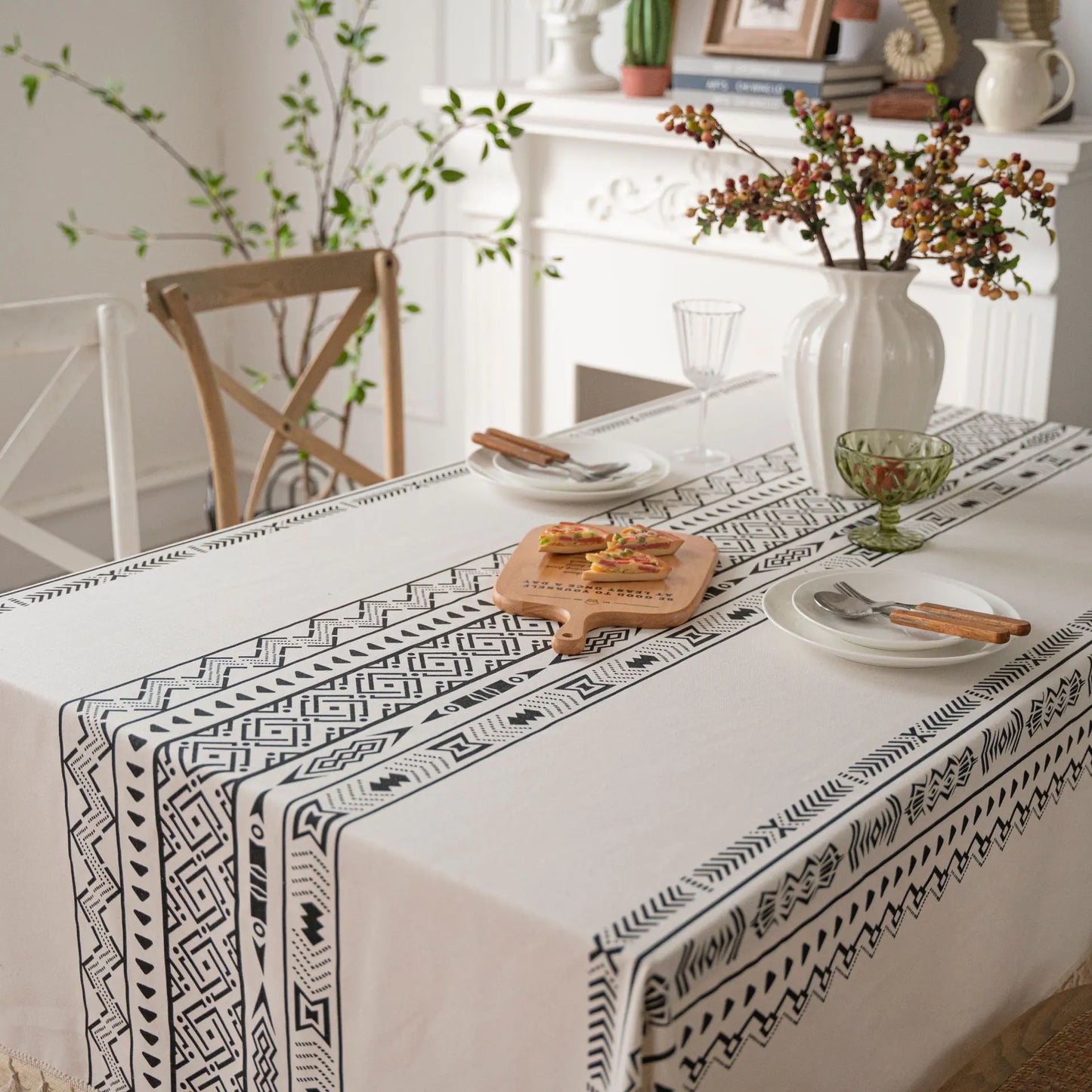 Dining table with a black and white patterned tablecloth, plates, and cutlery.