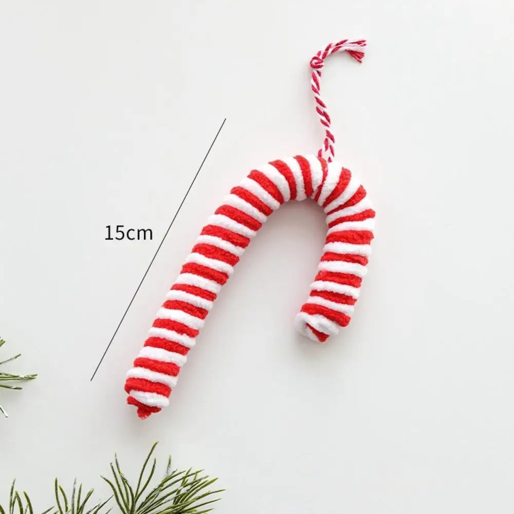 Red and white striped candy cane-shaped toy on a light gray background with greenery at the bottom.