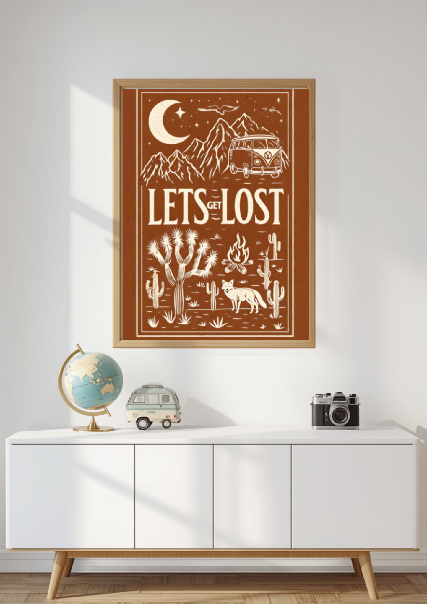 Retro camper van wall art displayed in a natural oak frame above a modern white sideboard with a decorative globe, miniature camper van and vintage camera in a bright contemporary living room.