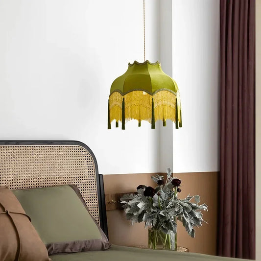 Green pendant lamp hanging above a bed with a vase of flowers on a nightstand.