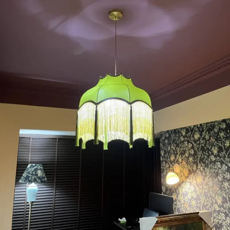 Green pendant lamp hanging in a room with floral wallpaper and a window.