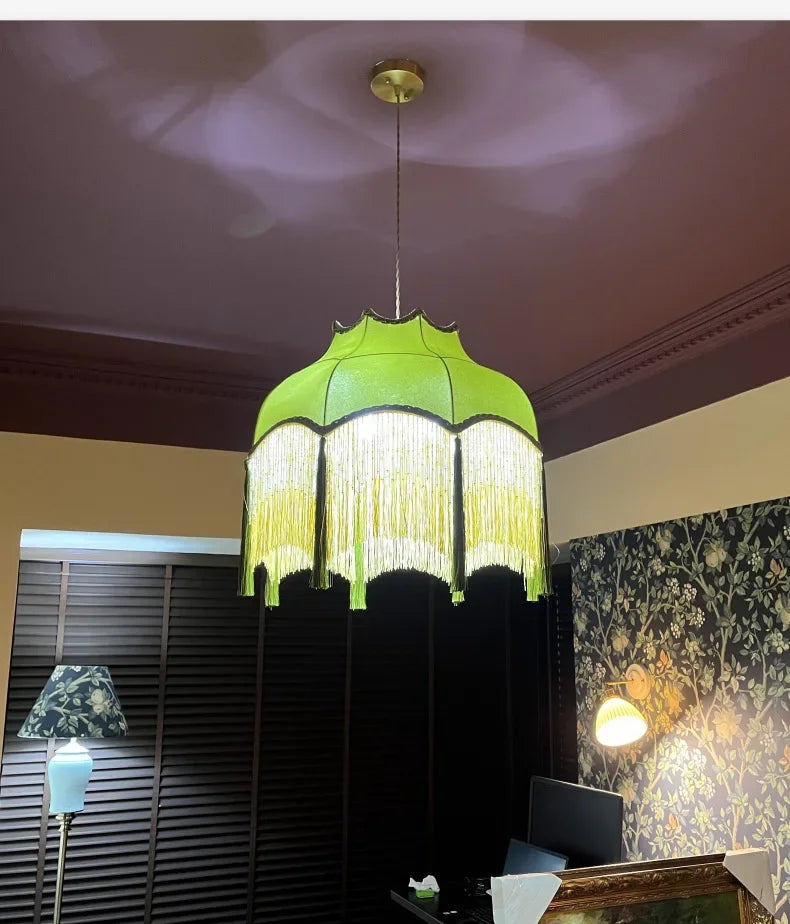 Green pendant lamp hanging in a room with a window and wall decor.