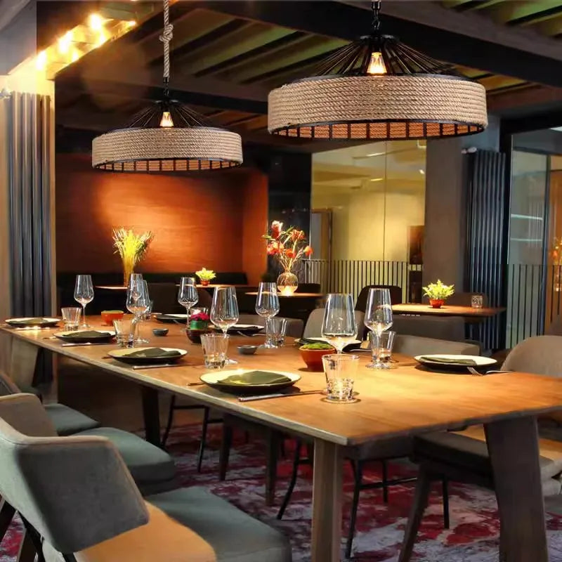 Rustic hemp rope pendant light with industrial metal frame and warm LED bulb, ideal for dining room or café decor.