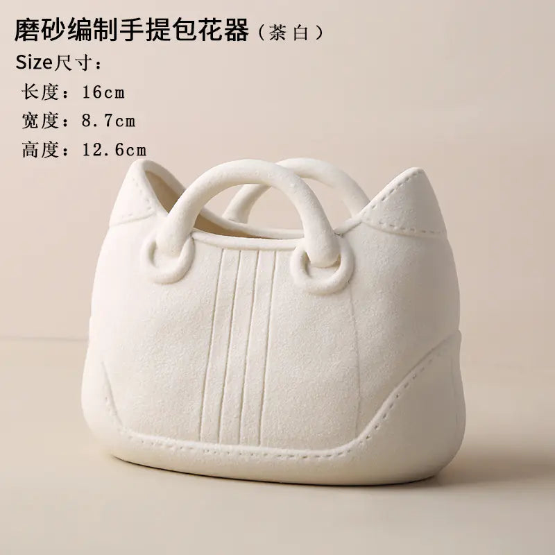 White handbag-shaped flower pot with text on a beige background