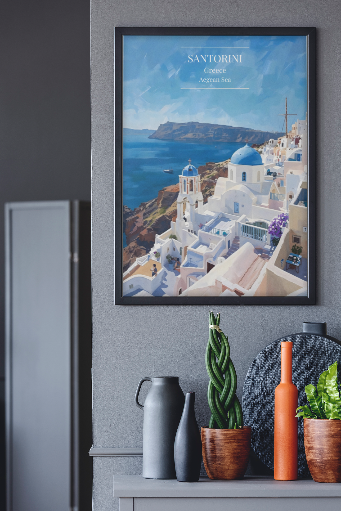 Framed artwork of Santorini on a gray wall above a shelf with decorative items.