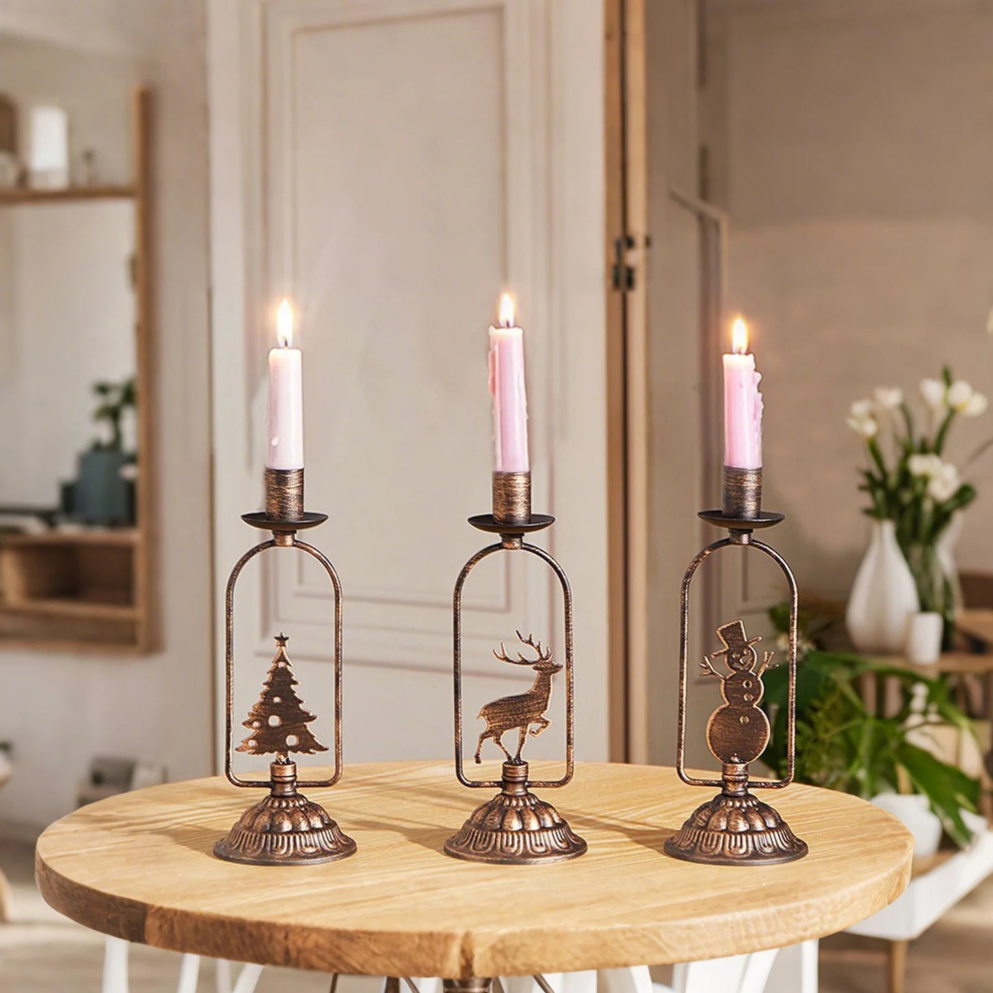Three decorative candle holders with lit candles on a wooden table.
